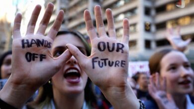 معترضی که روی دست های خود عبارت های HANDS OFF و OUR FUTURE را نوشته است