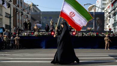 زنی با پرچم بزرگ ایران در یک مراسم رسمی