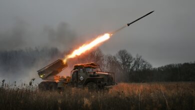 این عکس یک پرتابگر راکت چندگانه (MLRS) متعلق به نیروهای نظامی روسیه را نشان می‌دهد که در حال شلیک یک موشک از میان یک میدان یا منطقه علفزار در غروب یا هوای گرگ و میش است. شعله‌ی عظیم و درخشان شلیک موشک به وضوح دیده می‌شود که نور آن بر روی خود پرتابگر و محیط اطراف سایه انداخته است. موشک با سرعت در حال اوج گرفتن به سمت آسمان تاریک و ابری است. پس‌زمینه تصویر توسط درختان لخت و مه‌آلود احاطه شده است که جوی متشنج و نظامی ایجاد می‌کند. این تصویر نمادی از قدرت آتش، حملات دوربرد و درگیری‌های جاری در جنگ اوکراین است.