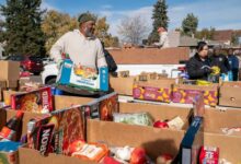 داوطلبان موسسه خیریه پارک هیل فود پنتری در حال پر کردن و مرتب کردن جعبه‌های اهدای غذا در طول توزیع غذای هفتگی - اطلس دیپلماسی