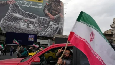 مردی در میدان انقلاب اسلامی در مرکز شهر تهران با پرچمی در دست در داخل ماشین در آستانه توافق ایران و آمریکا