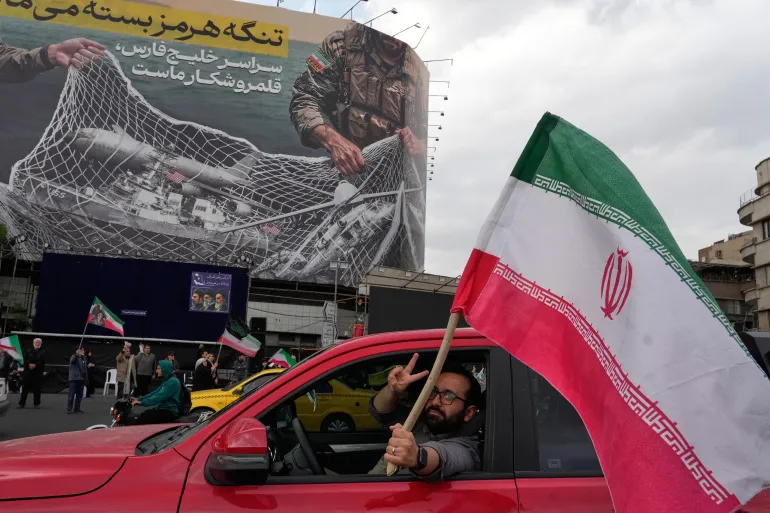 مردی در میدان انقلاب اسلامی در مرکز شهر تهران با پرچمی در دست در داخل ماشین در آستانه توافق ایران و آمریکا