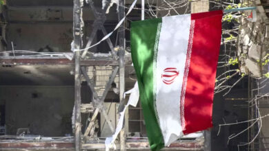 پرچم ایران در میان ویرانه های ناشی از بمباران