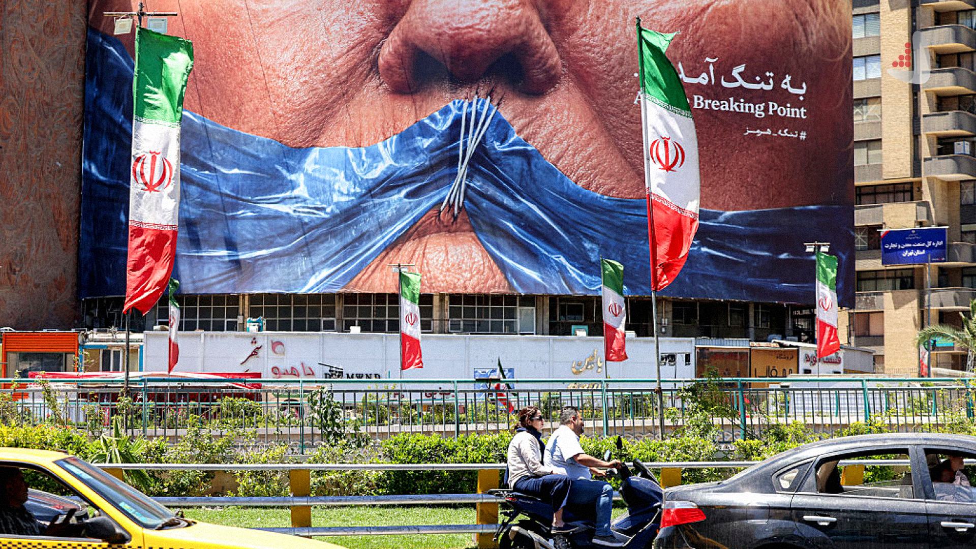 بیلبورد بزرگی در تهران با تصویر دهان بسته شده با پلاستیک آبی و عبارت به تنگ آمدن در کنار پرچم‌های ایران