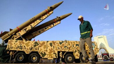 دو فروند موشک بالستیک ذوالفقار روی پرتابگر متحرک با استتار دیجیتالی در میدان آزادی تهران با حضور یک عابر پیاده.