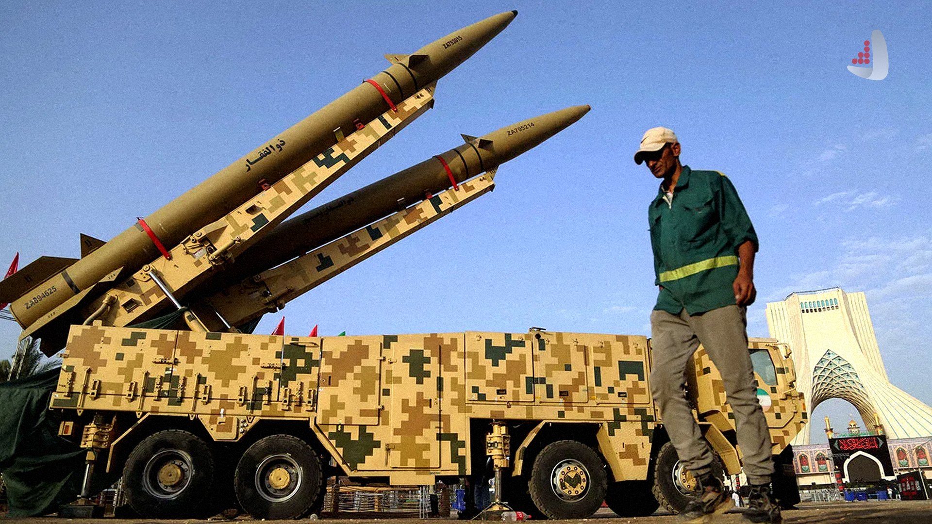 دو فروند موشک بالستیک ذوالفقار روی پرتابگر متحرک با استتار دیجیتالی در میدان آزادی تهران با حضور یک عابر پیاده.