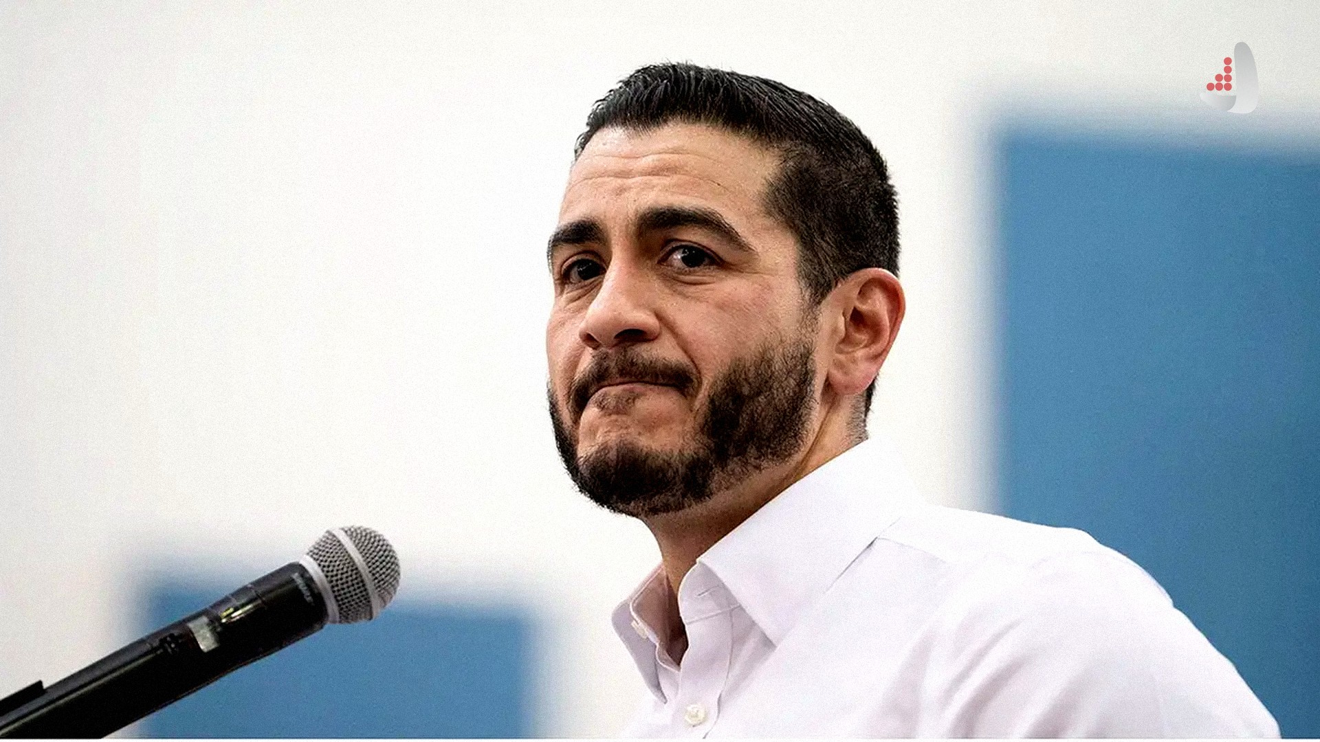 پرتره دکتر عبدال السید پزشک و سیاستمدار مسلمان آمریکایی با پیراهن سفید پشت تریبون و میکروفون
