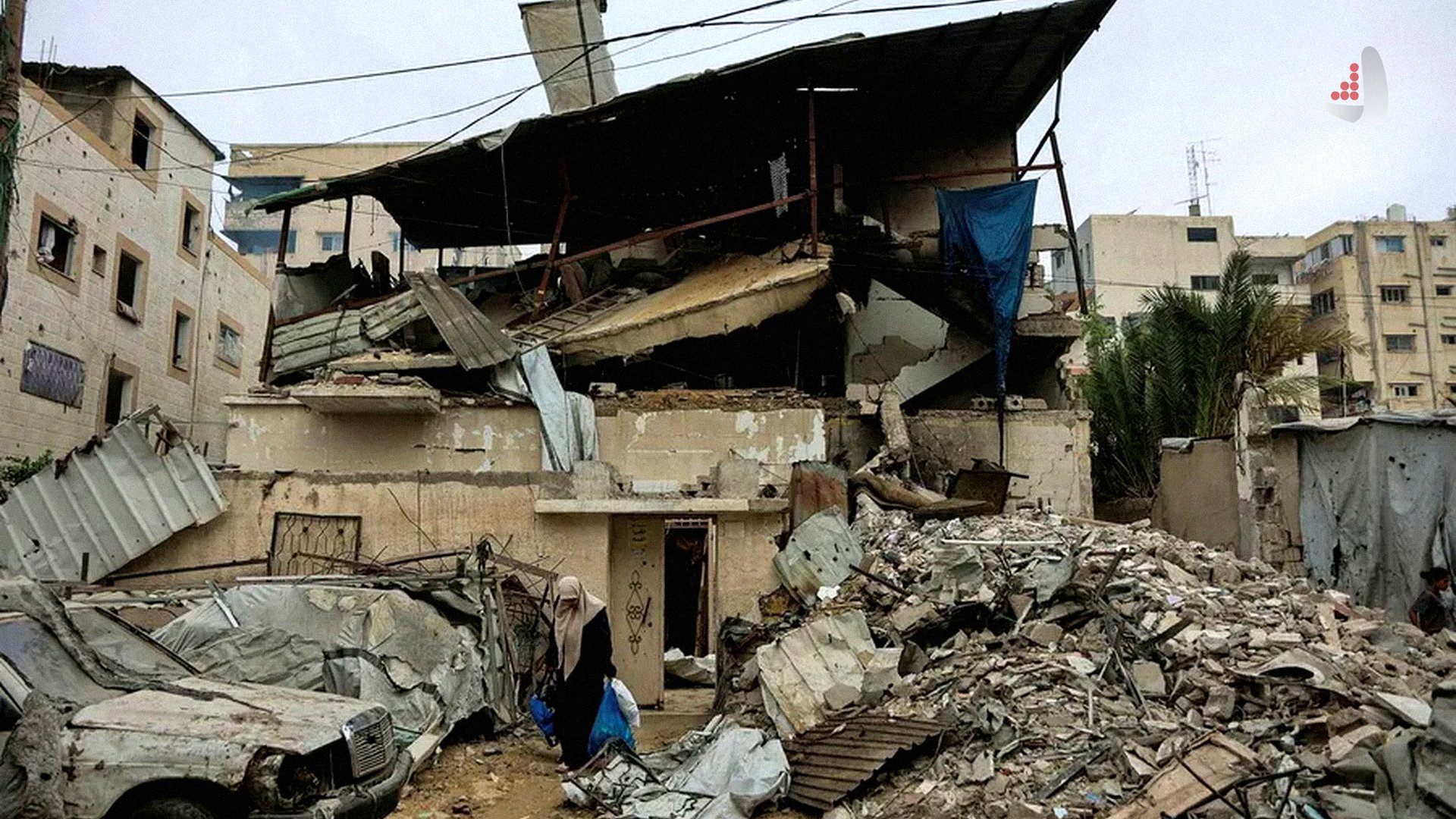 زن فلسطینی در حال عبور از کنار آوار ساختمان تخریب‌شده و خودروی درهم‌شکسته بر اثر حملات هوایی اسرائیل در غزه