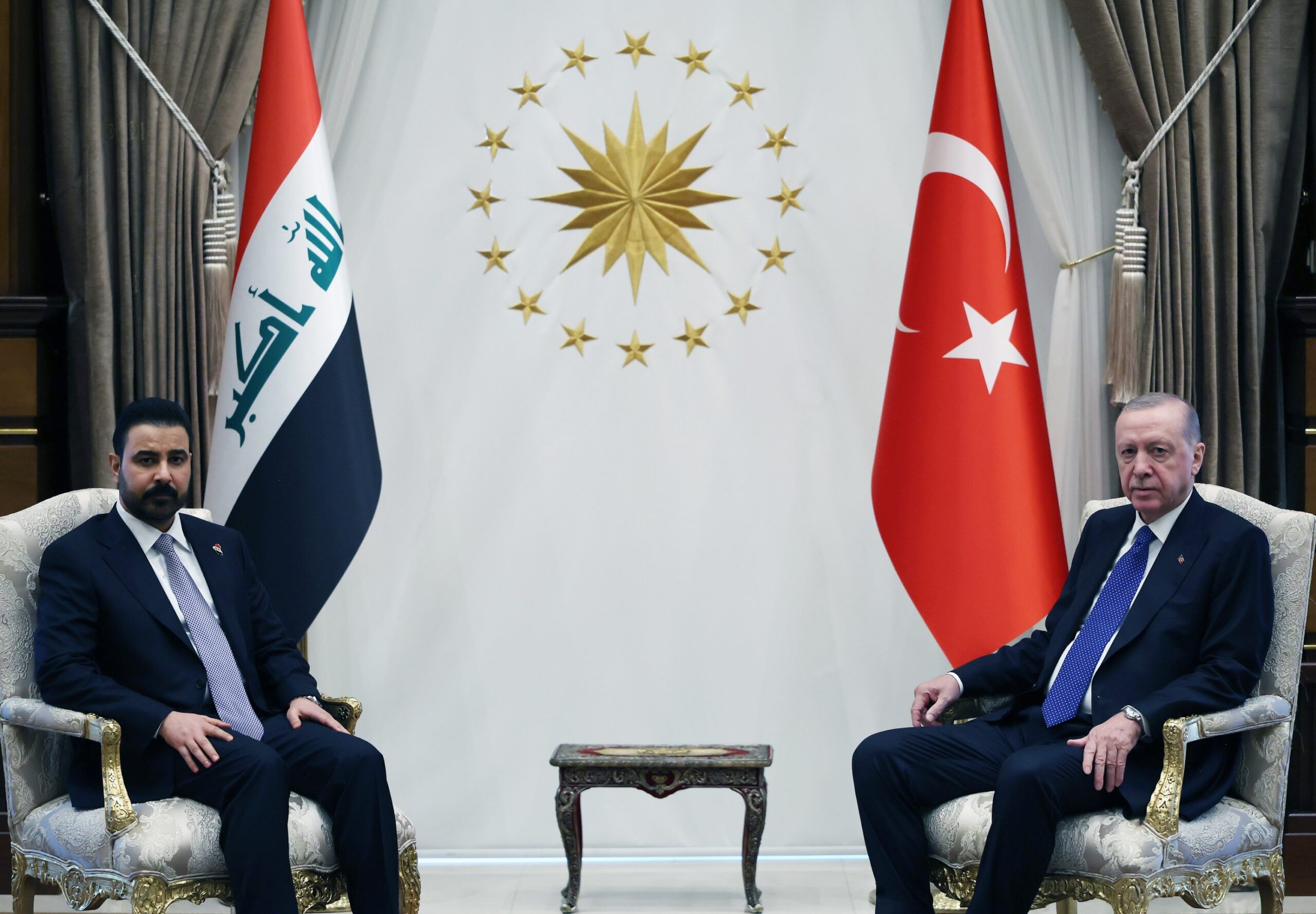 محمد شیاع السودانی نخست وزیر عراق و رجب طیب اردوغان رئیس جمهور ترکیه روی صندلی‌های مجلل در کنار پرچم‌های عراق و ترکیه و نشان ریاست جمهوری ترکیه