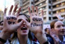 معترضی که روی دست های خود عبارت های HANDS OFF و OUR FUTURE را نوشته است
