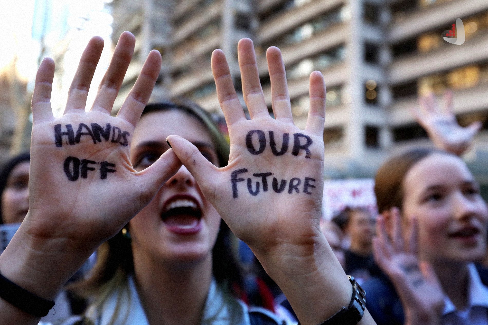 معترضی که روی دست های خود عبارت های HANDS OFF و OUR FUTURE را نوشته است