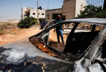 مرد فلسطینی در کنار خودروی سوخته در کرانه باختری